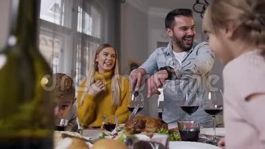 幸福快乐的一家人坐在宴会桌旁，看着微笑迷人的父亲切烤火鸡
